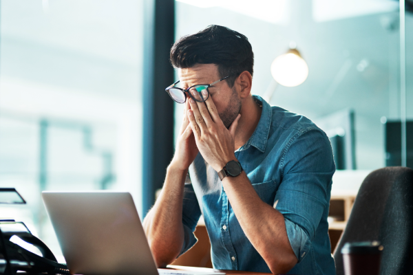 Stressed man at laptop frustrated with IT support – considering switching managed service providers
