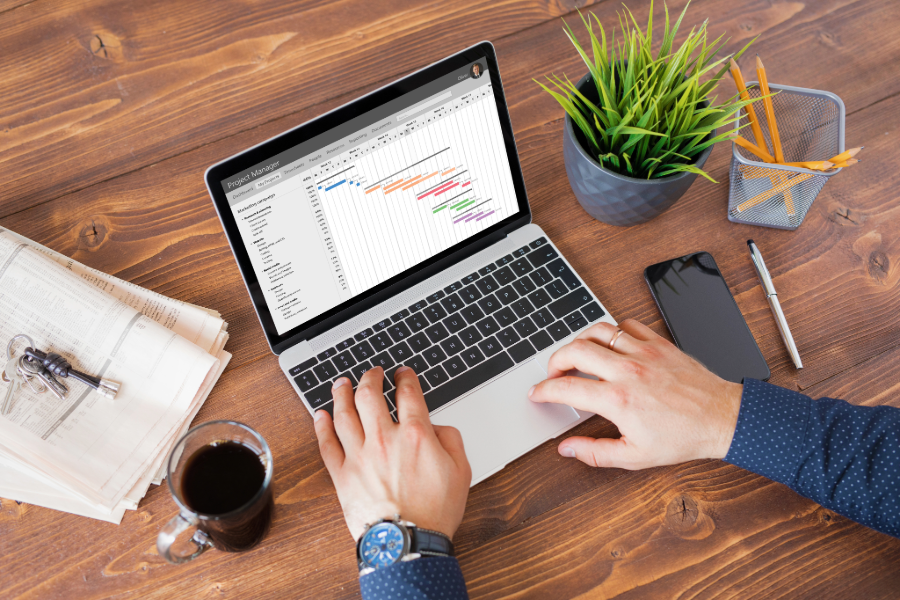 Person working on a laptop with a project management spreadsheet open, representing Google Workspace and Microsoft 365 tools