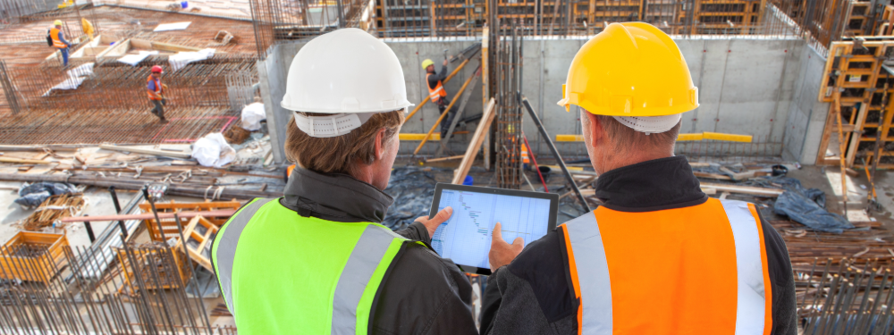 Two construction managers using a tablet on-site to manage project data and cybersecurity risks