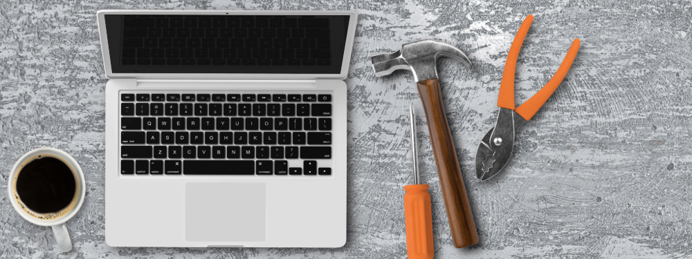 Laptop with construction tools and coffee cup representing IT support for construction companies