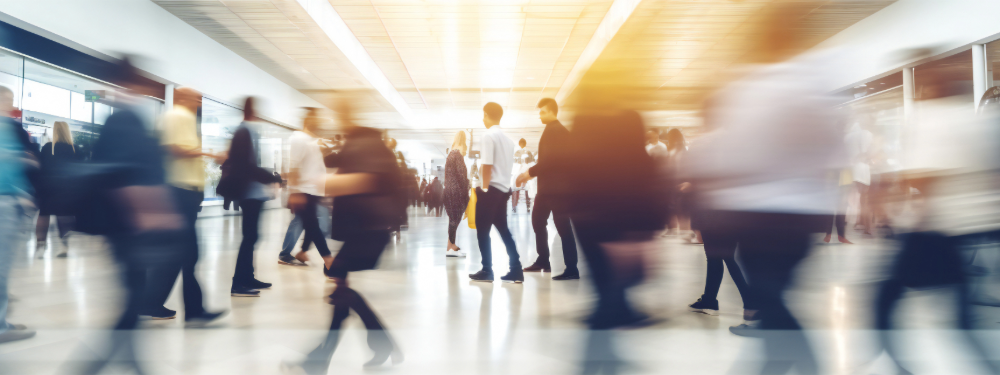 People walking through a bright, busy public space, representing government digital transformation and modern service delivery.