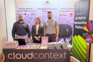 Cloud Context team at their sponsor booth at LGIT 2025 in Coffs Harbour with branded stand and giveaway wheel.